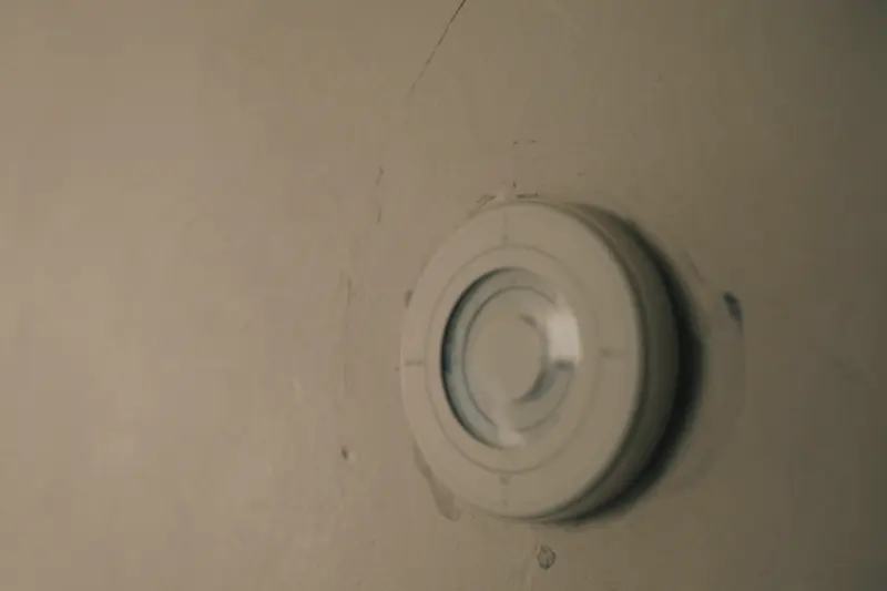A round white thermostat on a cream plaster wall, lit from the side